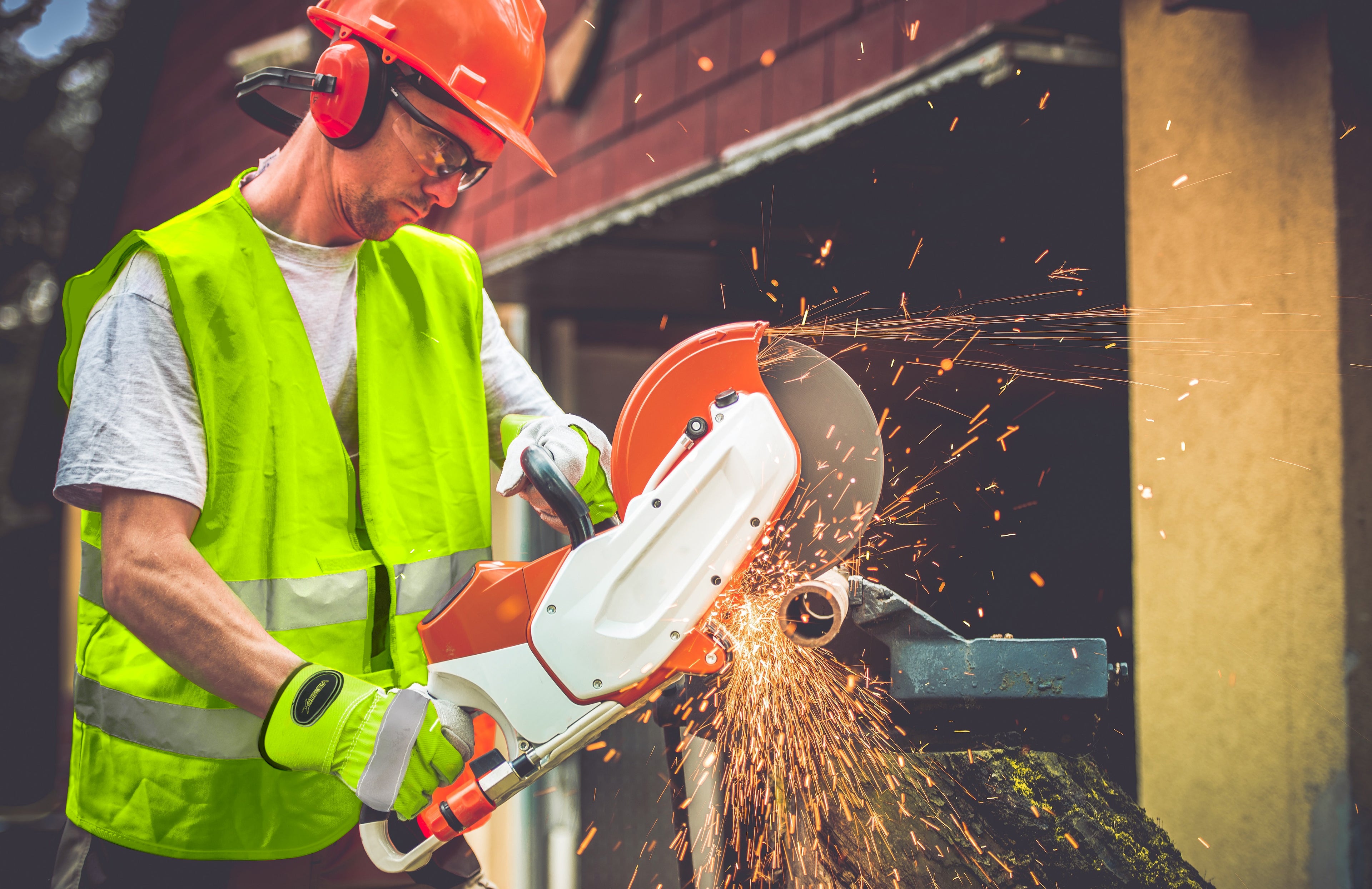 Man sawing through iron material while wearing a VisWERX vest and gloves.