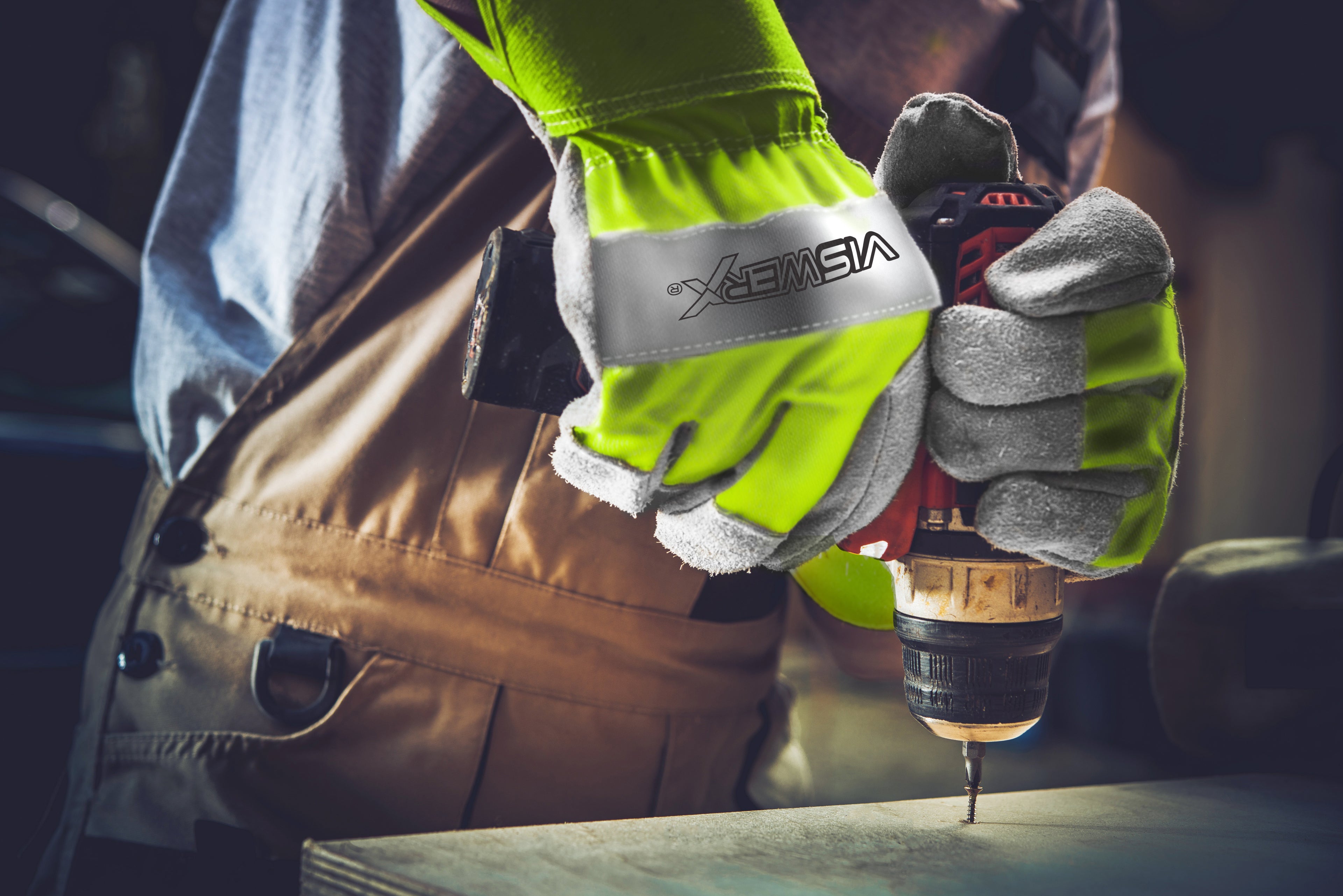 Individual drilling into a wood block while wearing VisWERX gloves.